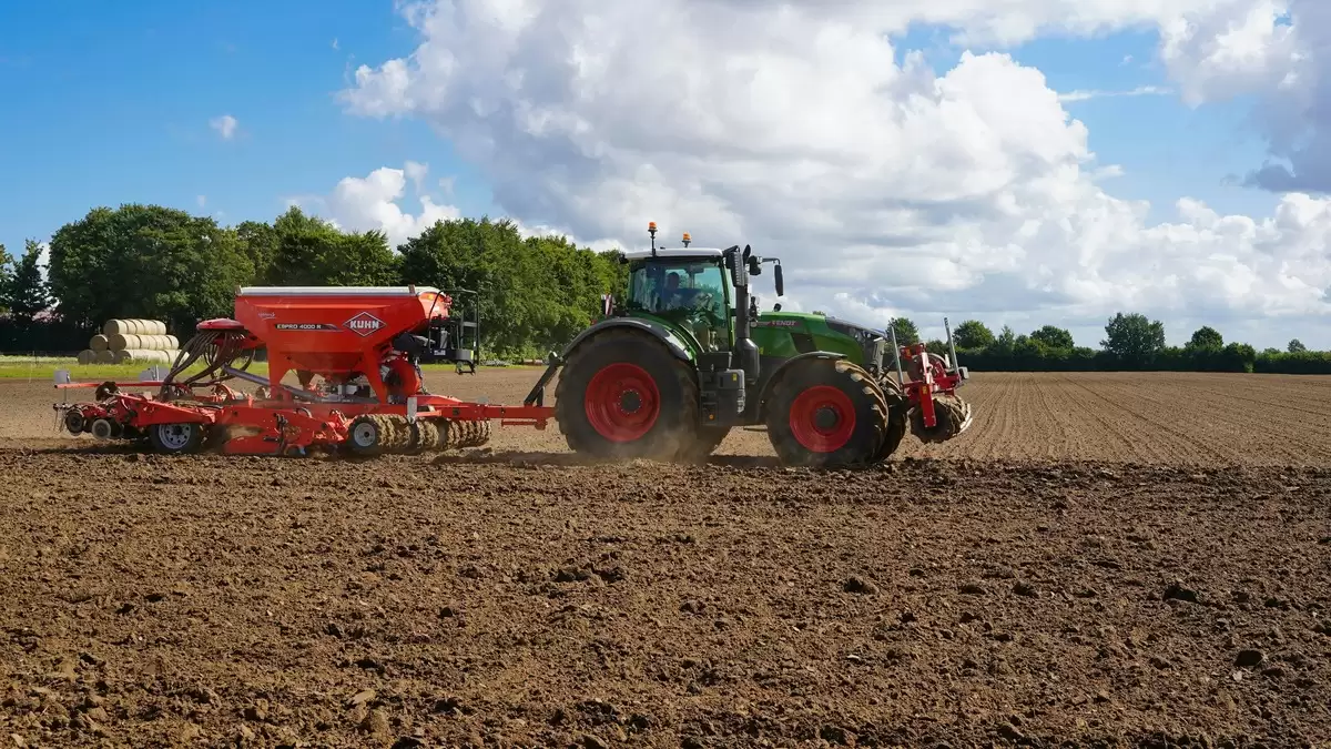 Semoir à céréales en modulation de dose attelé à un tracteur Fendt, en plein travail dans une parcelle préparée